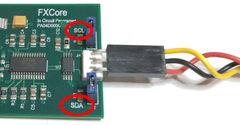 A green circuit board with wires and a black rectangular object with red circles

Description automatically generated